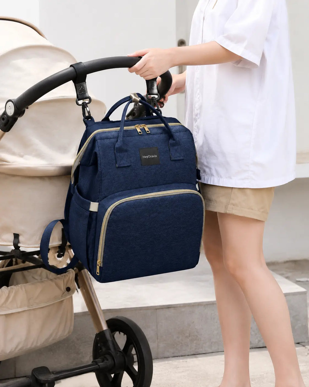 Heyoravix navy convertible diaper backpack hanging from a stroller handle