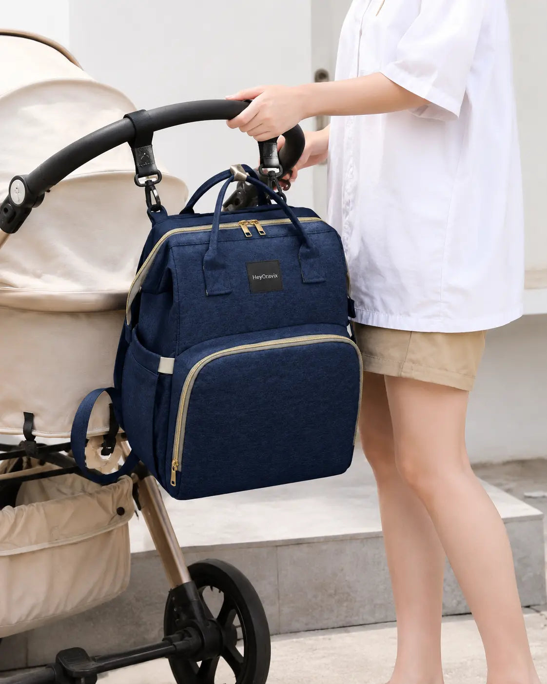 Heyoravix navy convertible diaper backpack hanging from a stroller handle