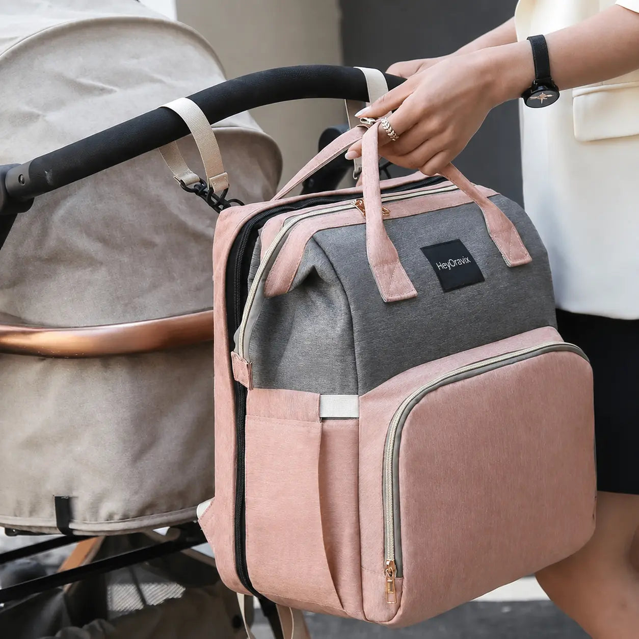 Heyoravix convertible diaper backpack in pink and grey attached to a stroller